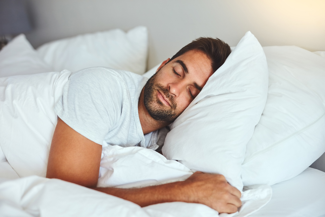 Cropped shot of a handsome young man sleeping comfortably in his bed at home