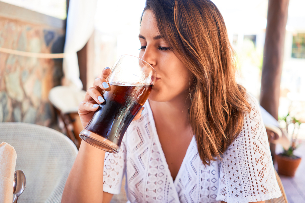 A young woman drinking diet soda outdoors