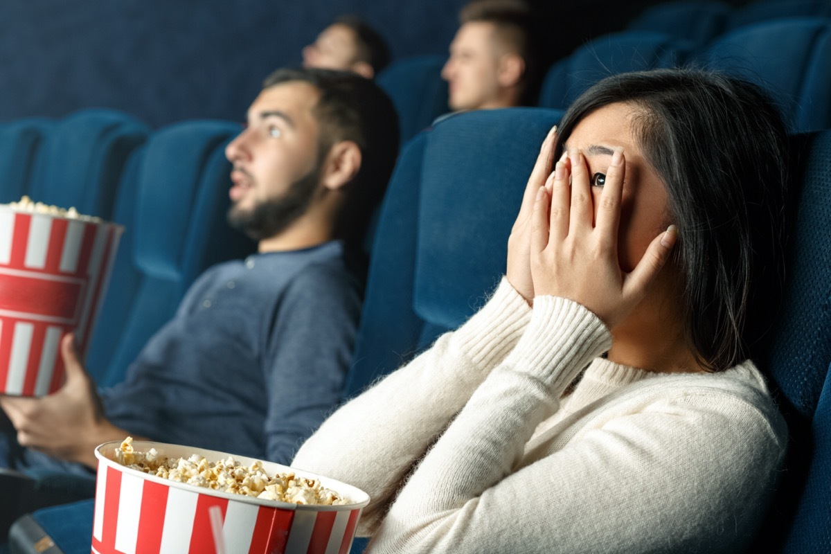 people eating popcorn in movie theater, focus on hands