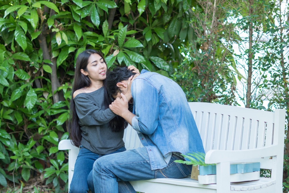 woman comforting a sad crying friend on a bench