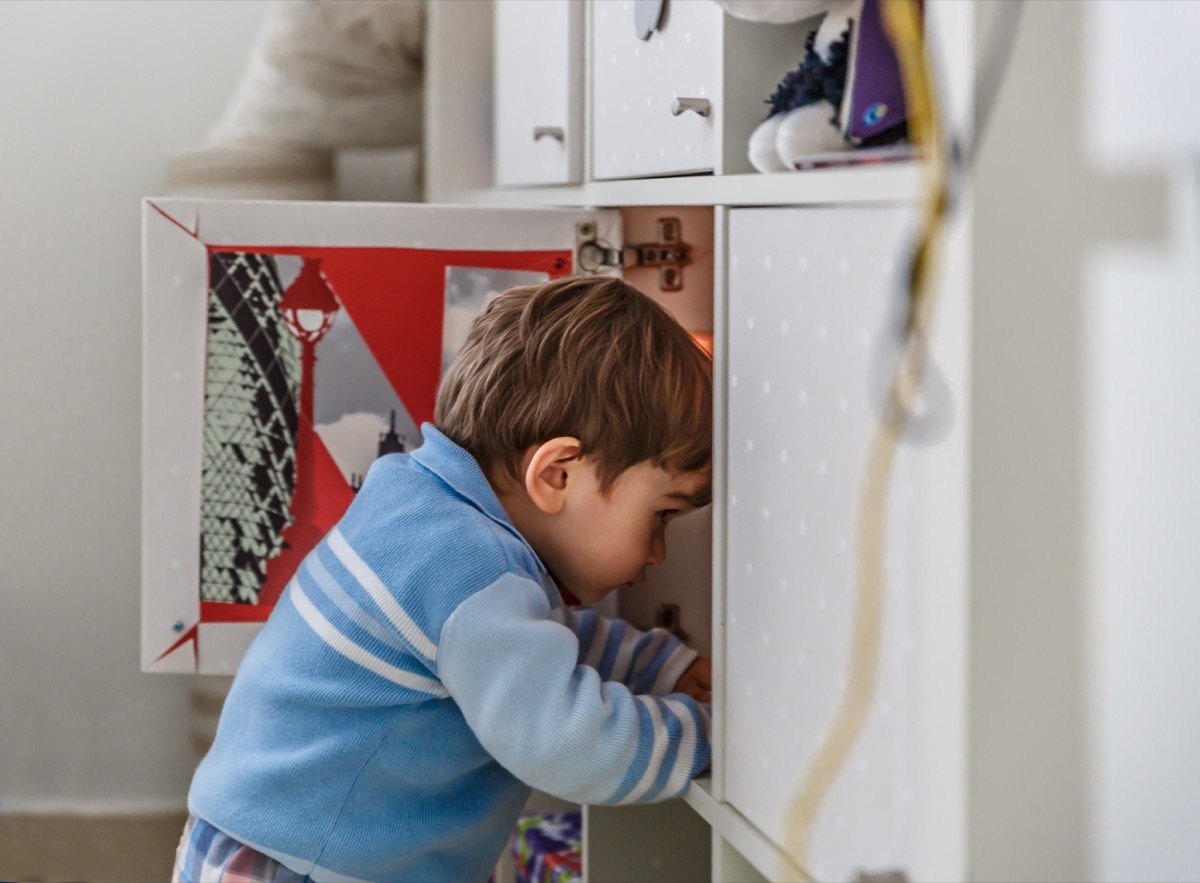 little boy looking inside cabinet