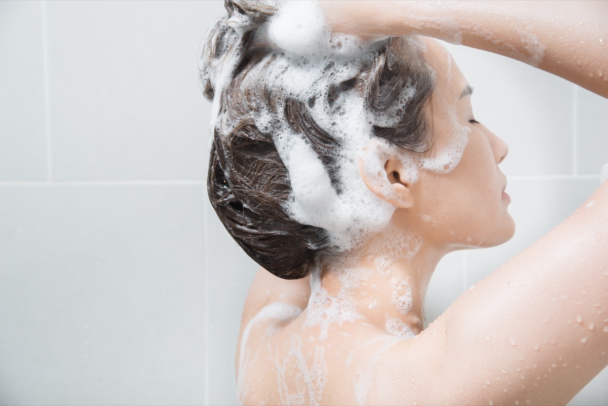 Woman in shower washing hair with shampoo