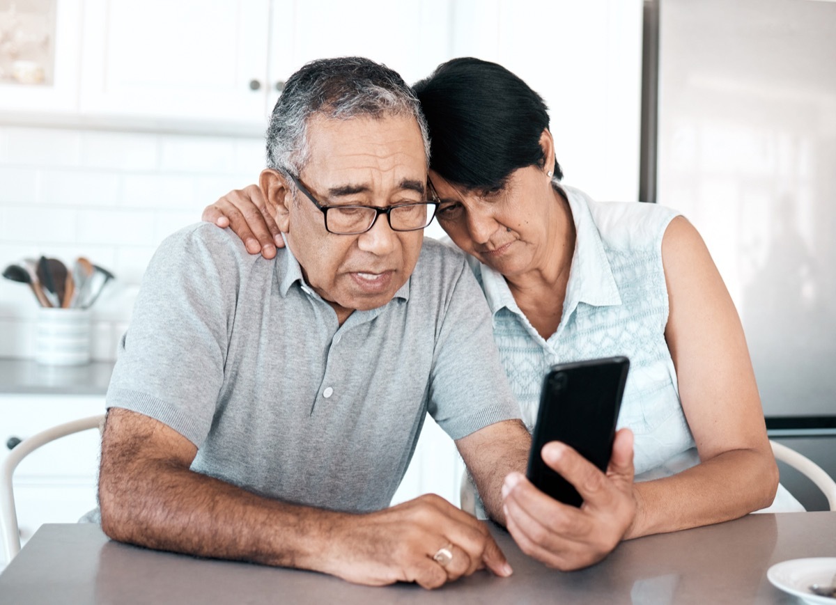 Shot of a senior couple looking unhappy while using a phone at home