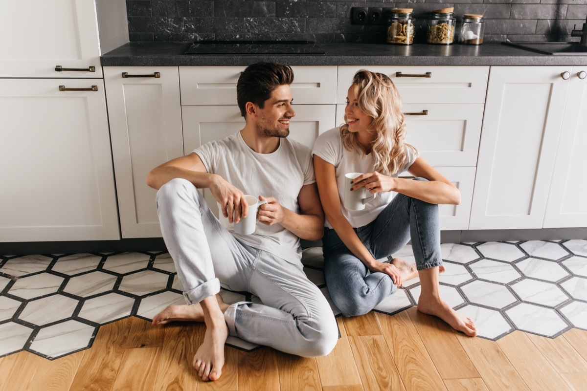 Young white man and woman drinking coffee on kitchen floor