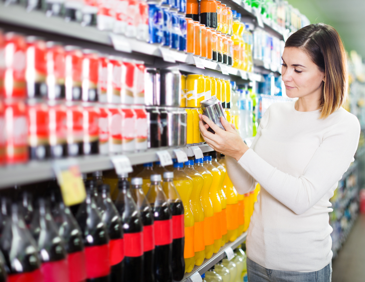 A young woman shopping for soda in a grocery store