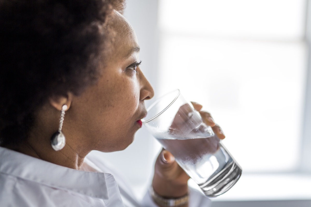 Black woman of middle age drinks water habits that slow down aging