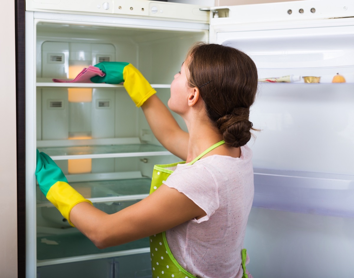 Woman cleaning fridge shelf