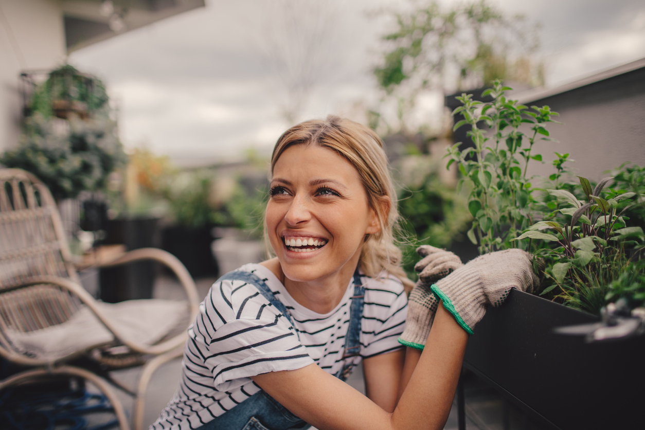 Young woman arranging plants in her rooftop garden