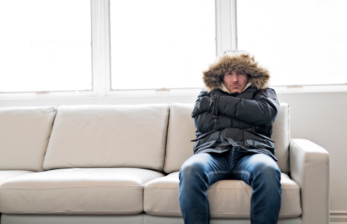 Cold man feeling sick bundled up indoors