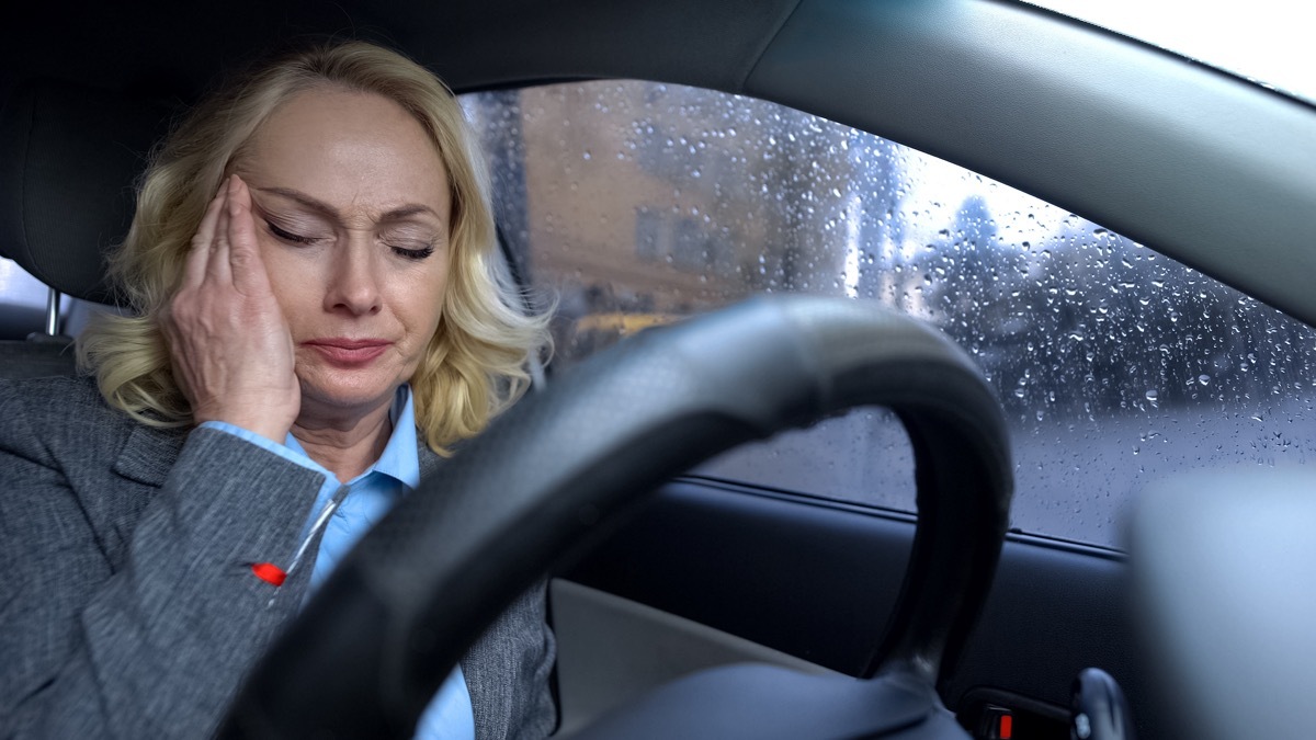 Mature business female sitting in a car on rainy day