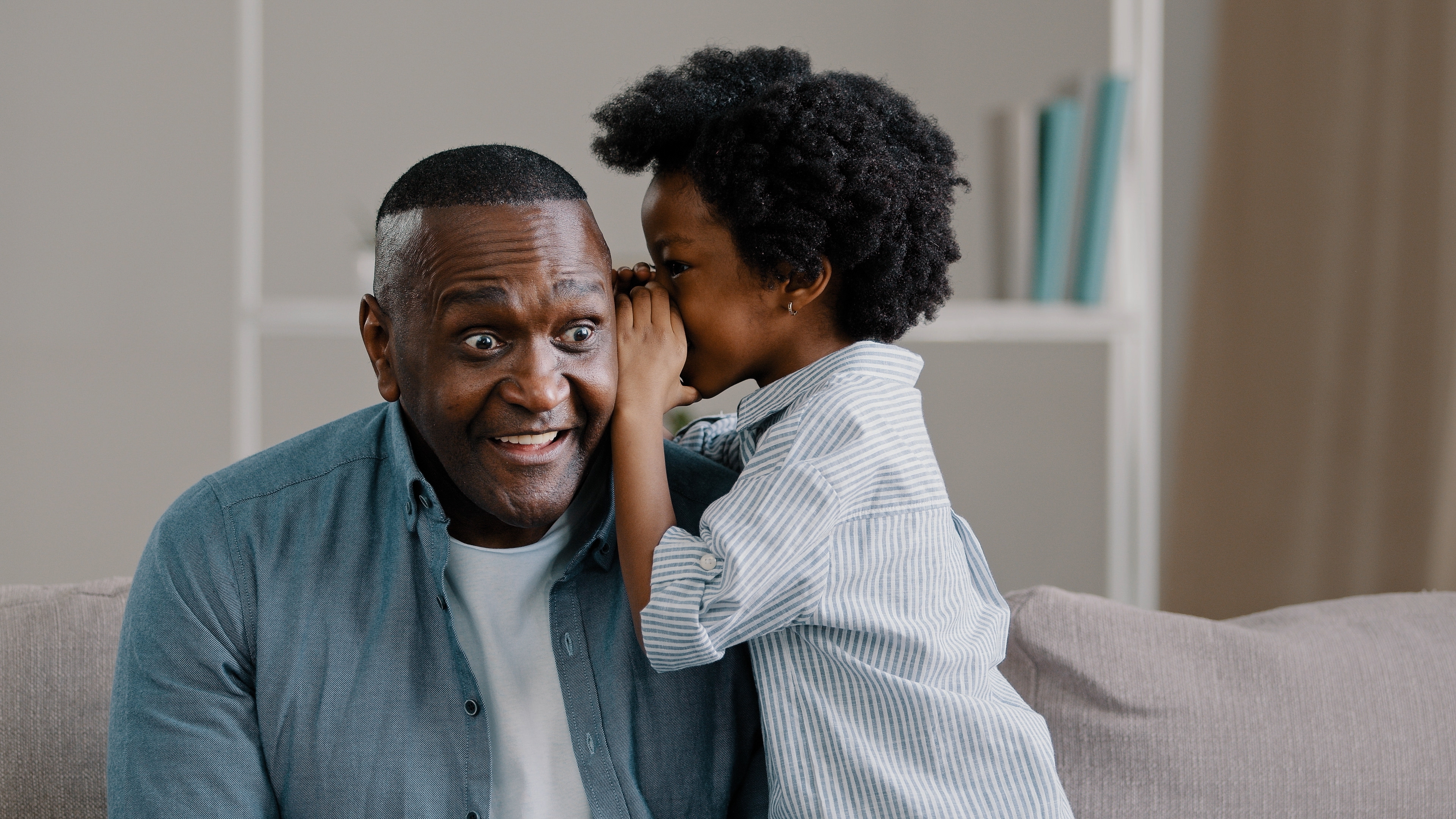 little girl whispering a corny joke to her father