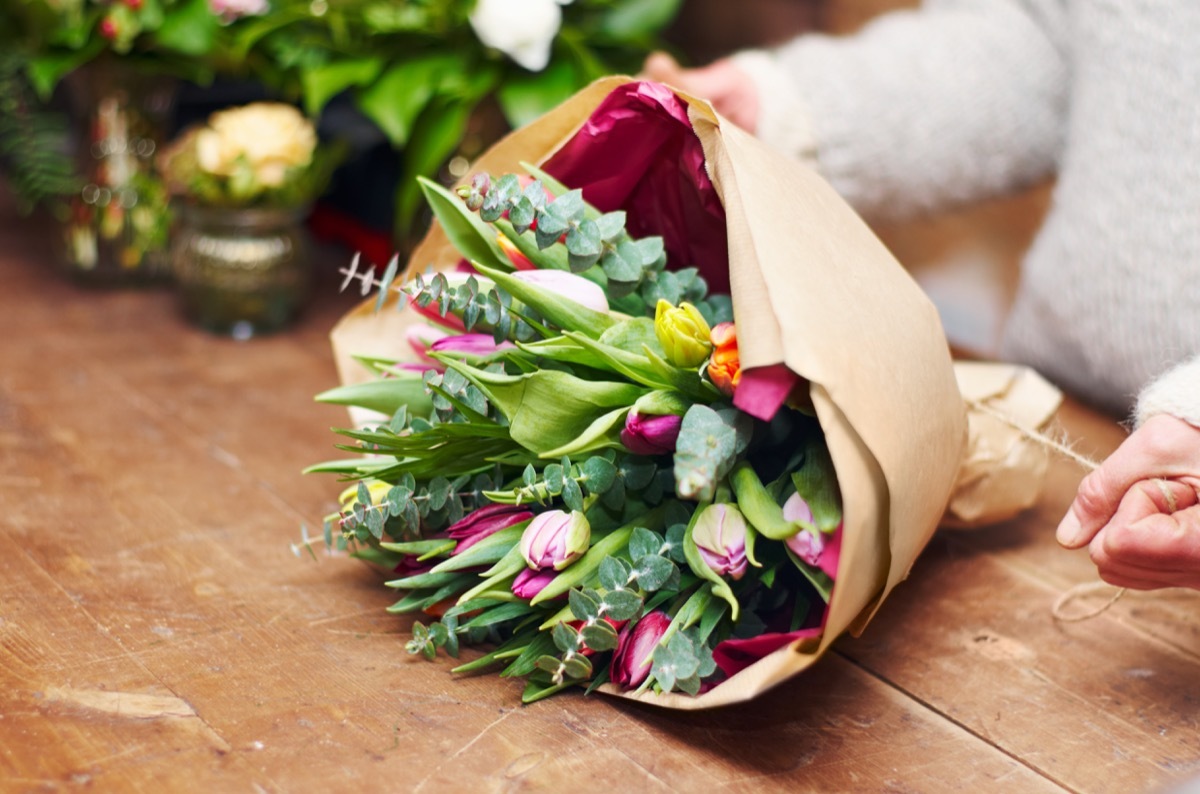 Cropped shot of a pretty floral bouquet being completed on a wooden counter top