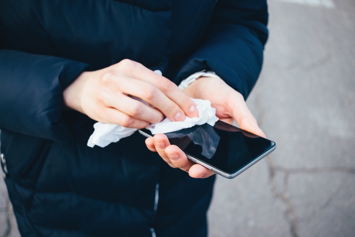 Person wiping down iPhone with disinfecting wipe