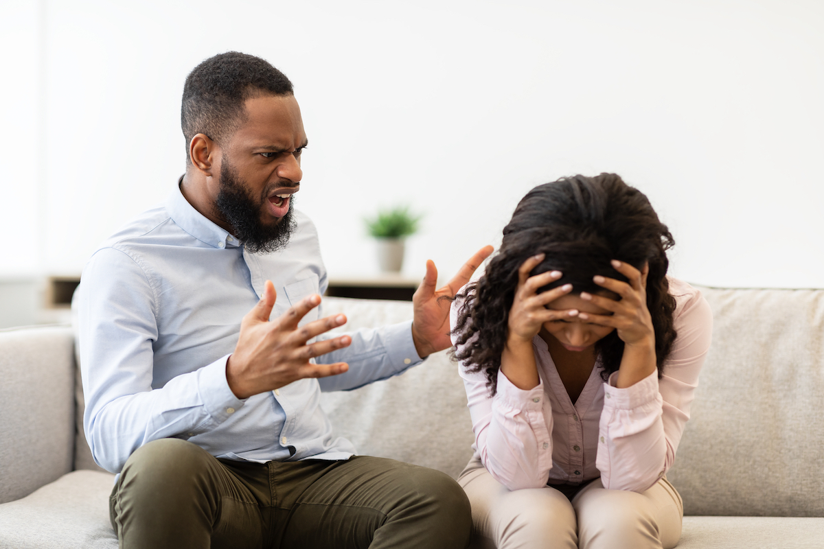 Young married black couple having fight, guy yelling at crying lady, gesturing at home.