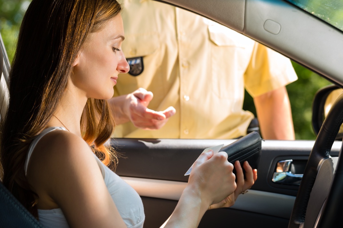 woman handing license to police officer during traffic stop things you should never do when getting pulled over