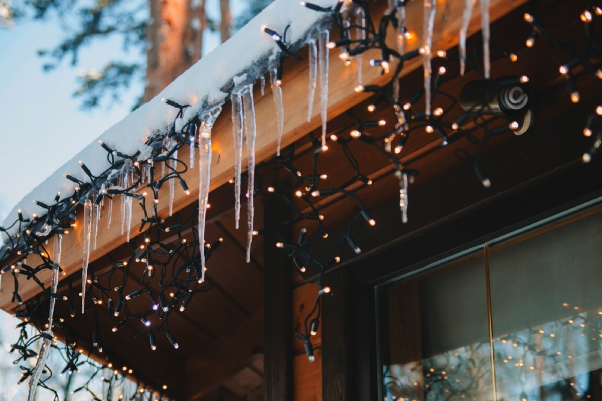 icicle lighting and icicles hanging off edge of snowy roof 