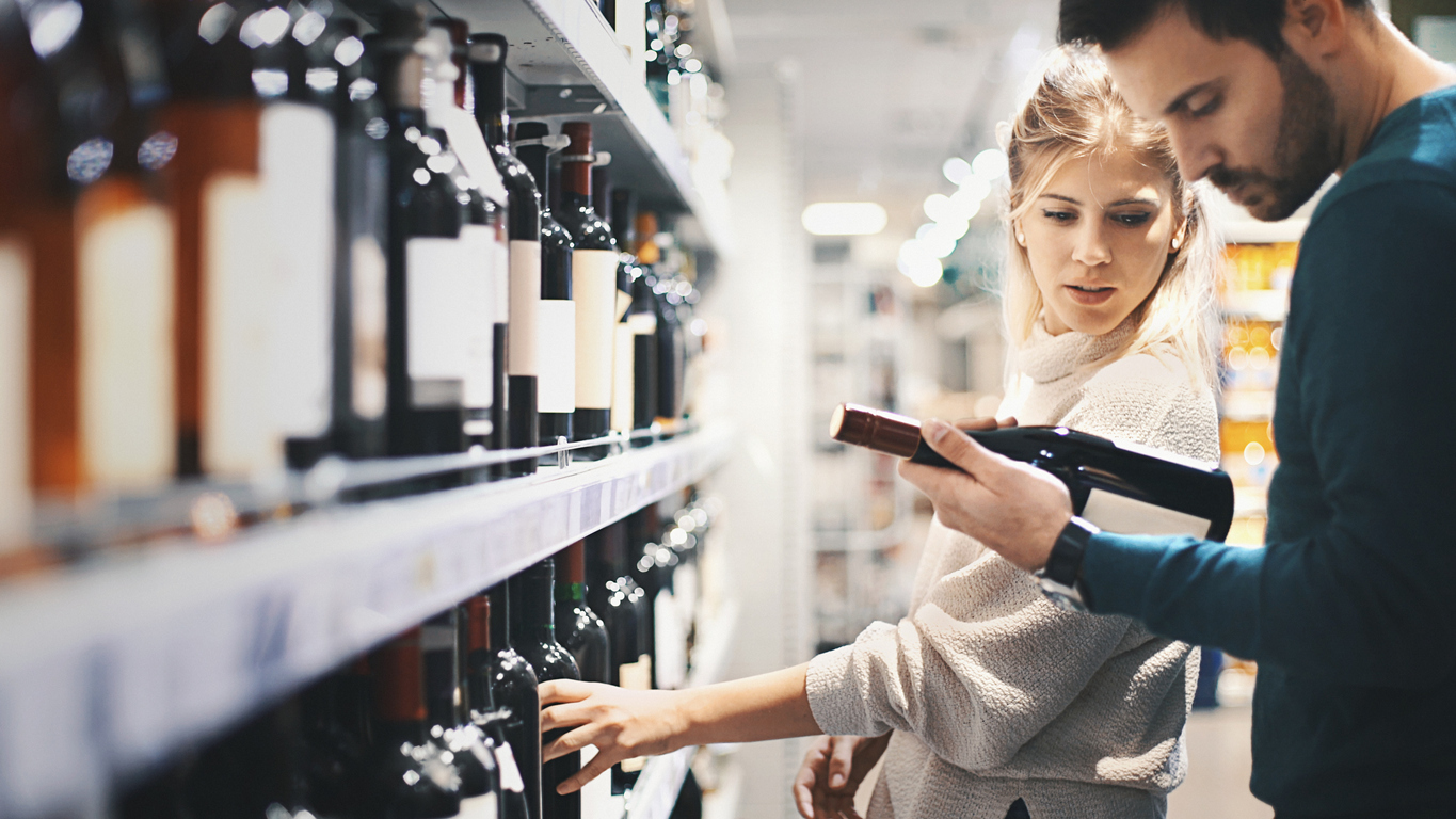 A young couple shopping for a bottle in a liquor store