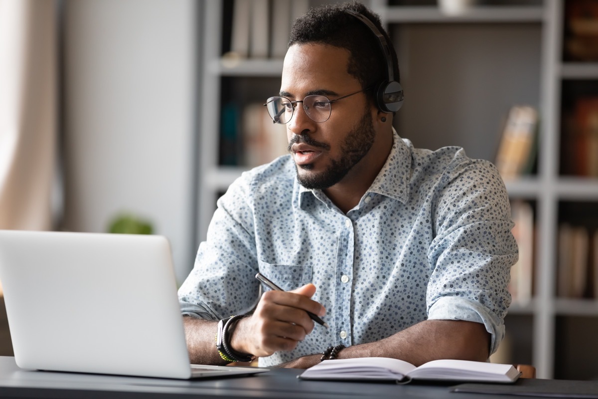 young black businessman taking notes while looking at laptop computer