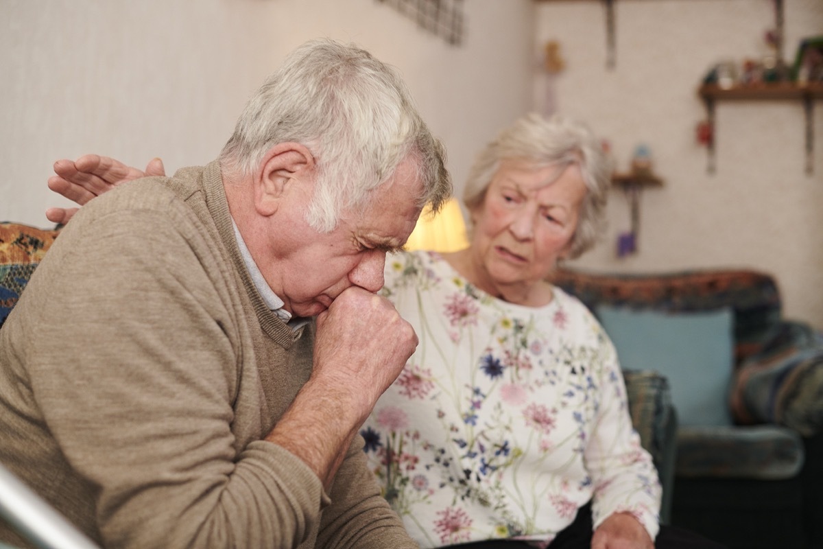 senior man with wife at home coughing badly, signs your cold is more serious