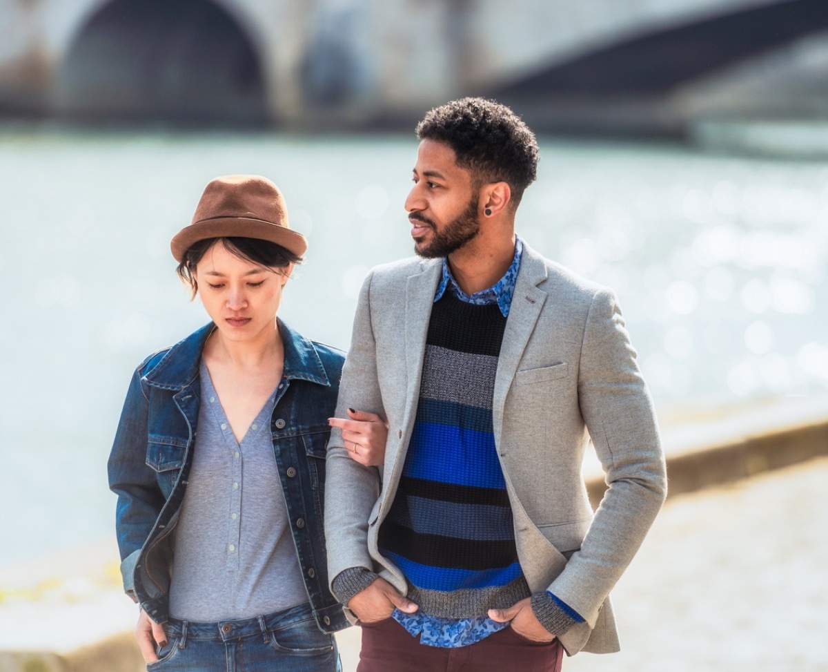 A young couple in discussion together as they walk by the Seine.