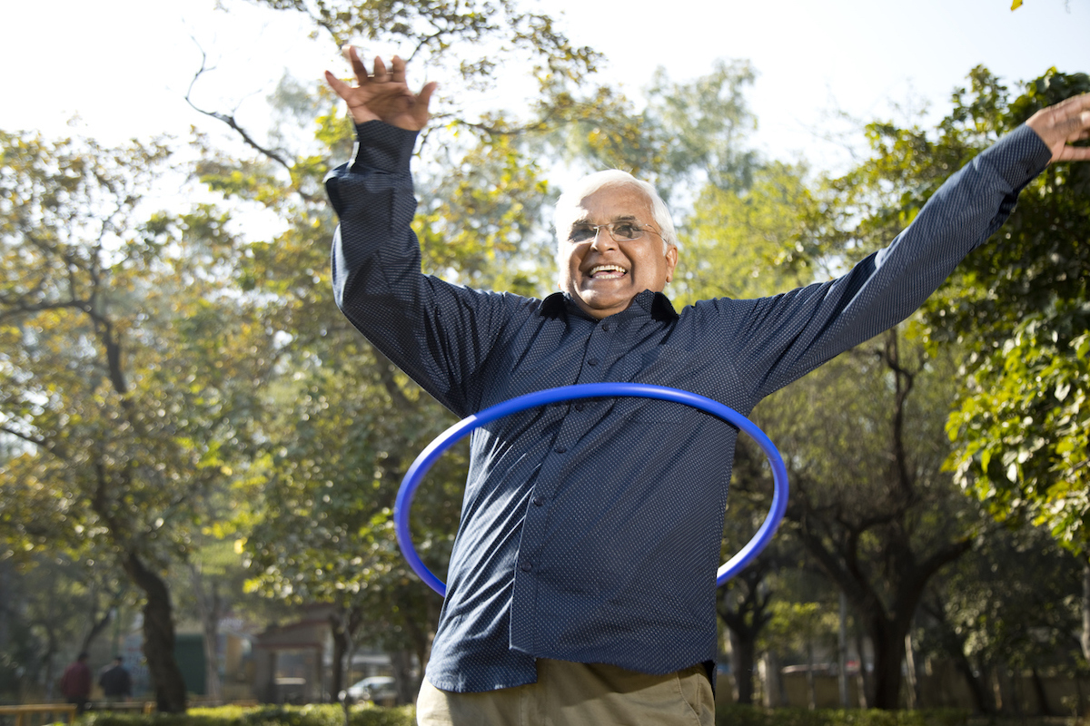 Happy senior man exercising with hula hoop at park