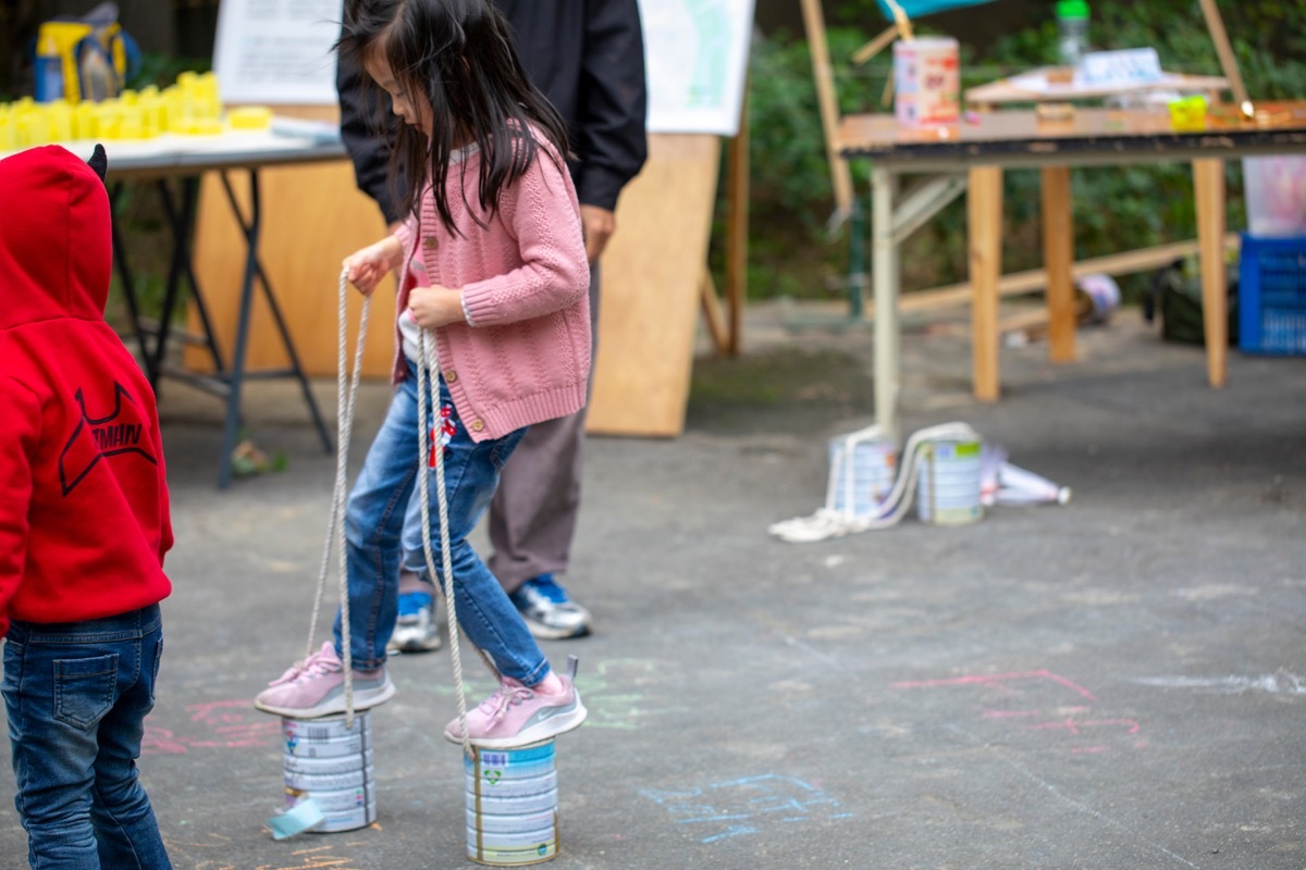 Girl walking outside with tin can stilts