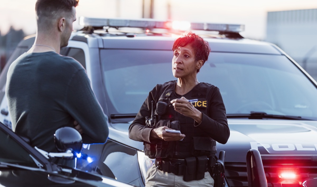 A policewoman taking a statement from a civilian outside her patrol car.