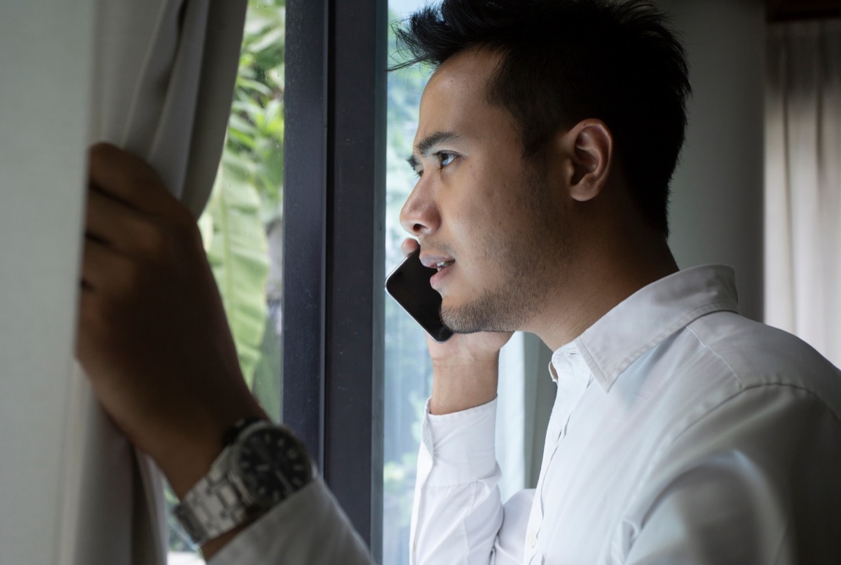 man talking on cell phone looking out window