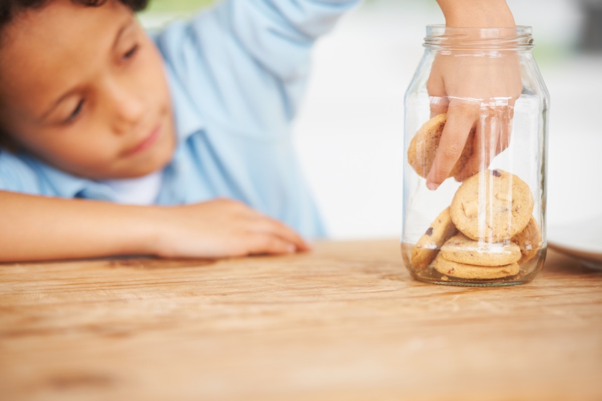 young boy taking a cookie from the cookie jar