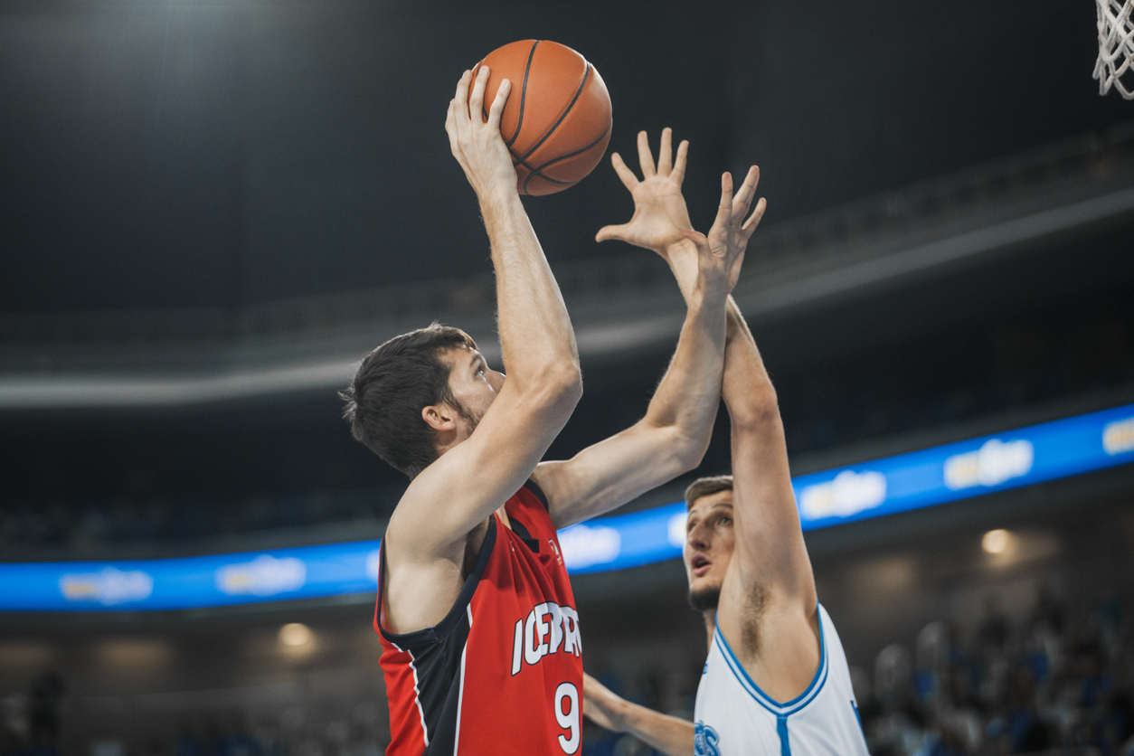 Basketball players chasing for ball during the match in court.