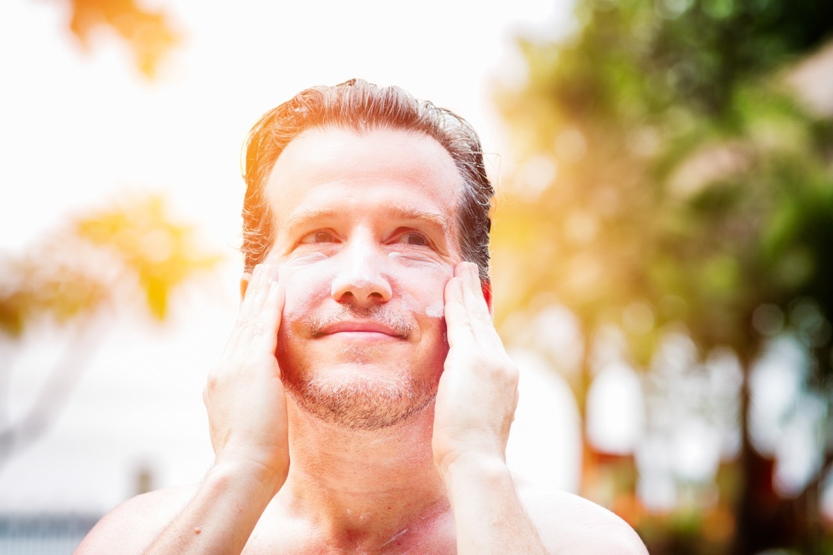 middle aged white man applying sunscreen to his face