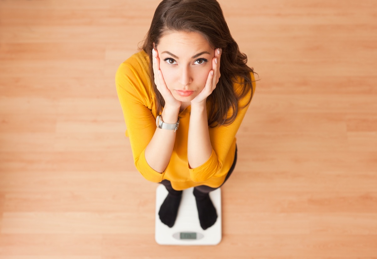 young brunette woman standing on a scale