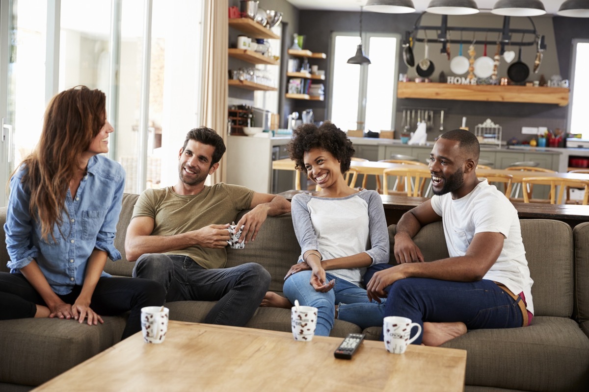 Couple Sitting On Sofa With Friends At Home Talking