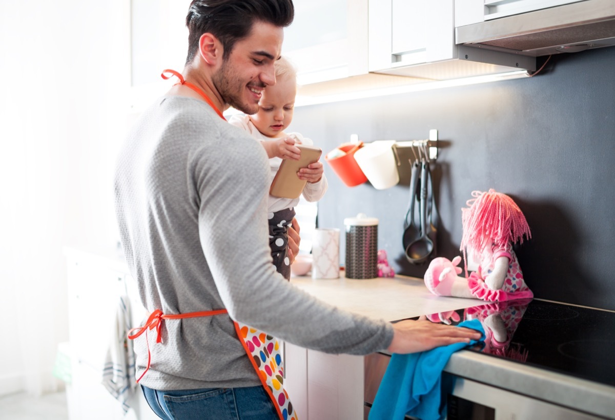 a father and his baby cleaning the kitchen counter