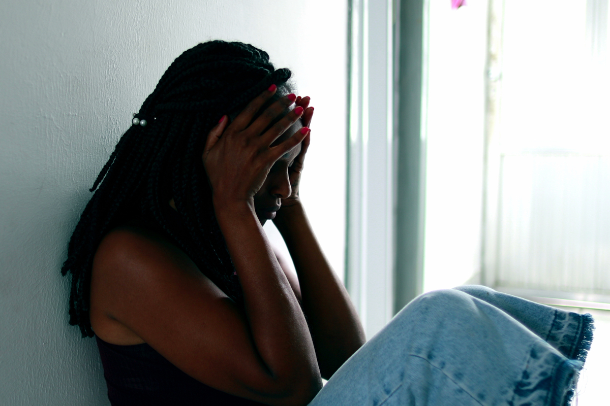 black woman sitting on floor holding her head