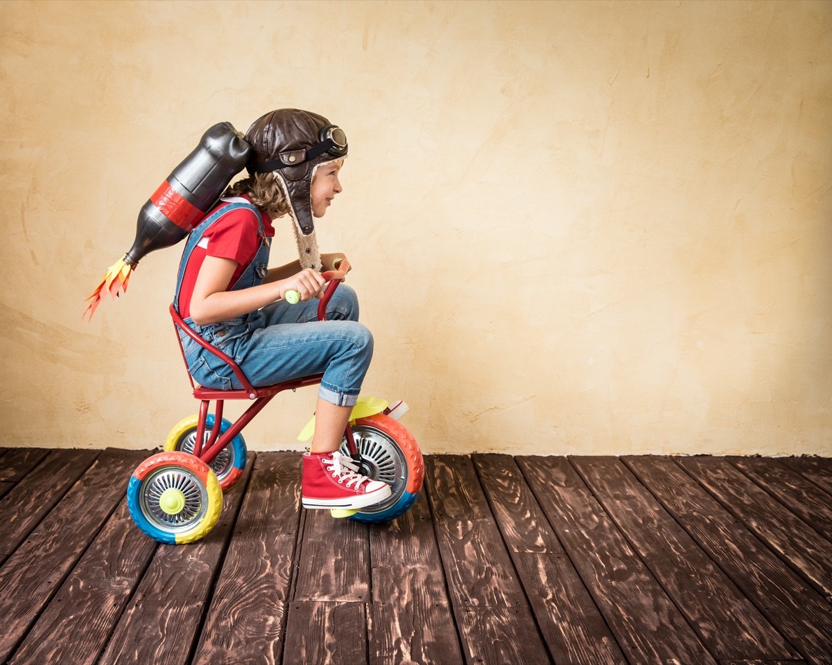 Kid wearing homemade jetpack and sitting on tricycle