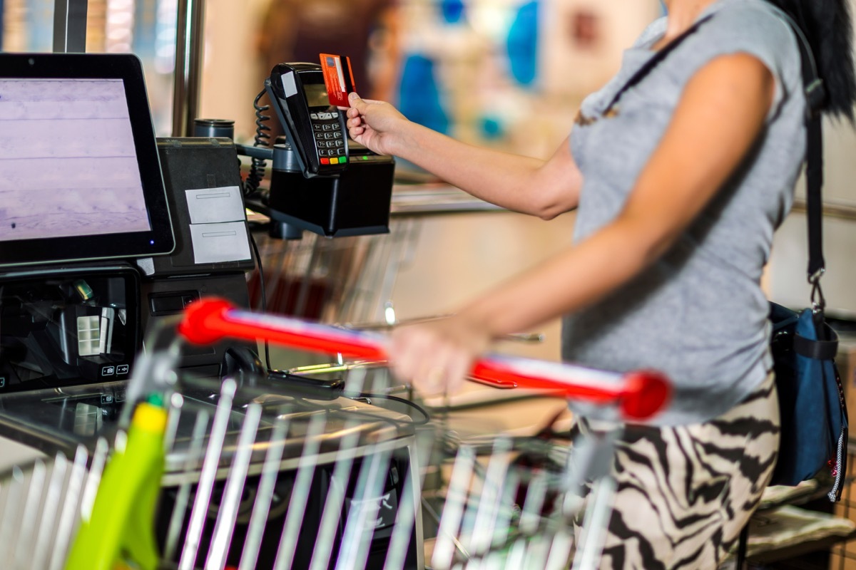 Woman with bank card buying food at grocery store or supermarket self-checkout