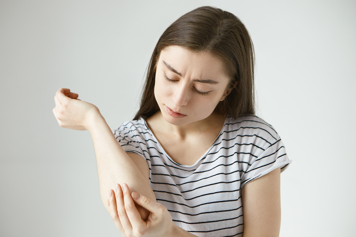 young woman studying skin on her arm