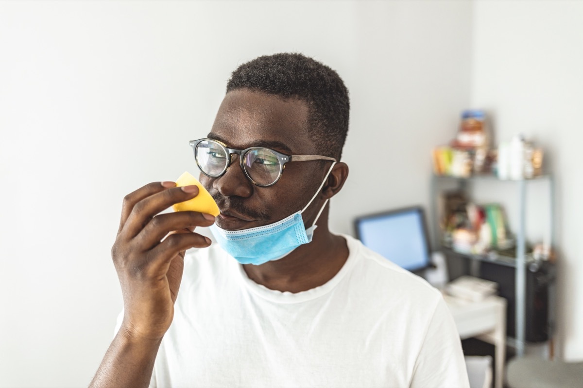 man Trying to Sense Smell of a Lemon at home during the day, smell blindness is one of the possible symptoms of covid-19.