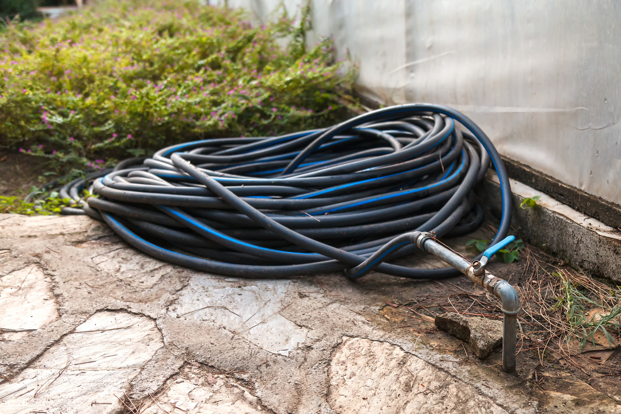 A coiled hose on the ground beside a house