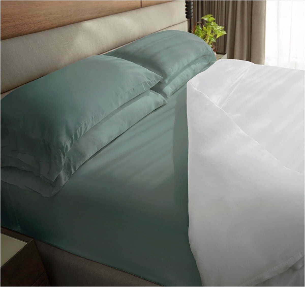 A set of Tahitian Breeze colored Cariloha Bamboo Bed Sheets on a mattress with a white comforter