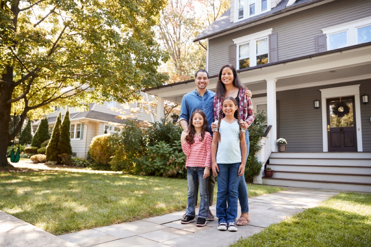 family standing in front of large suburban home, worst things about the suburbs