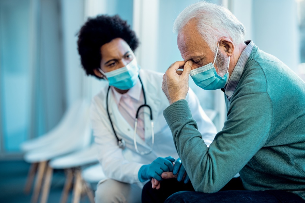 senior man holding his head in pain after getting bad news from a doctor at the hospital during COVID-19 pandemic.