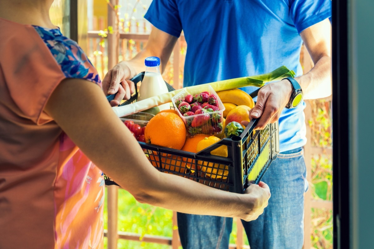 woman taking crate of dairy and produce from delivery person