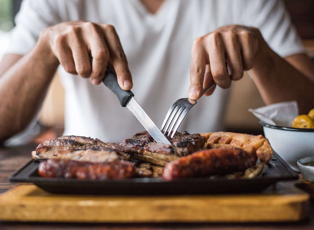 man cutting into steak with fork and knife