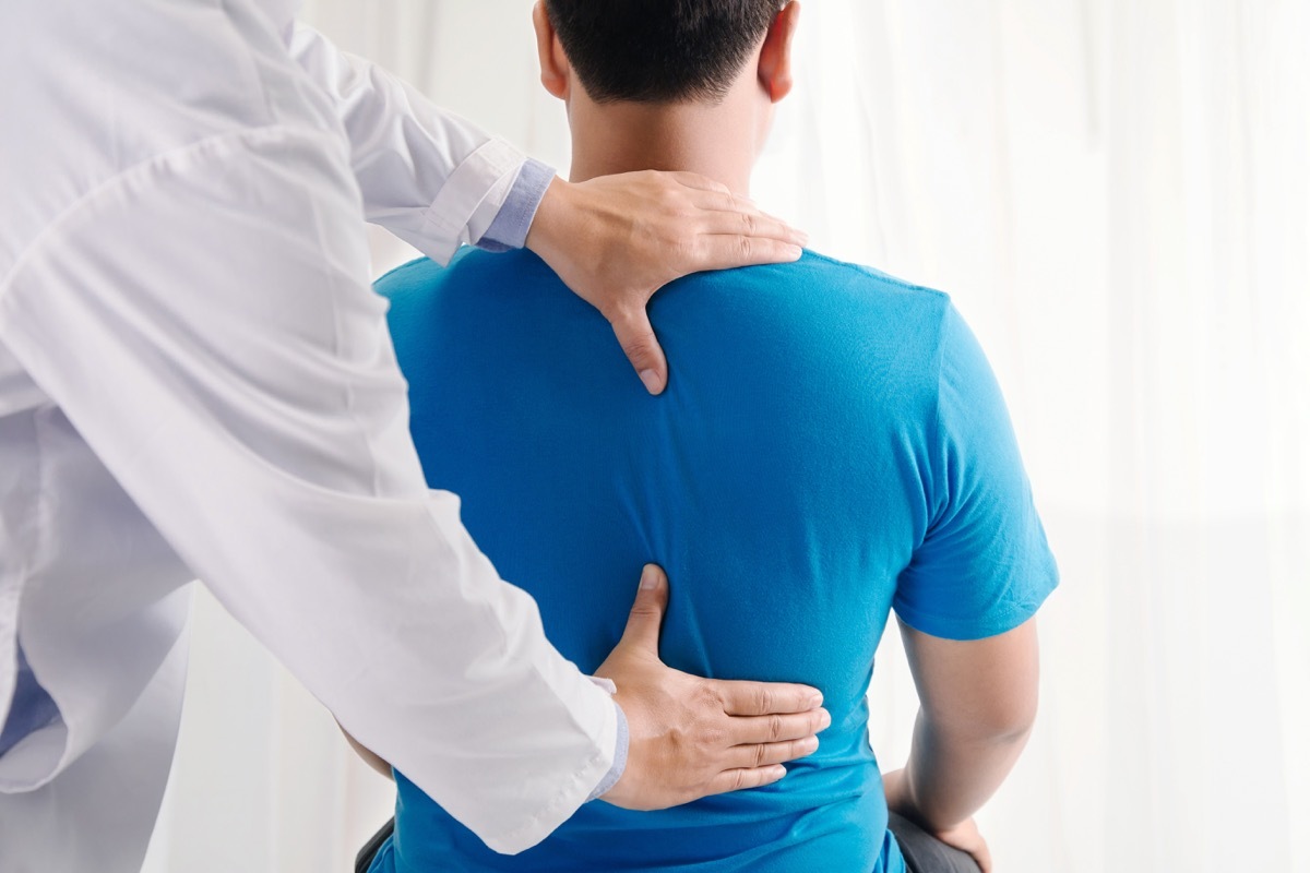 doctor touching man's back, back pain