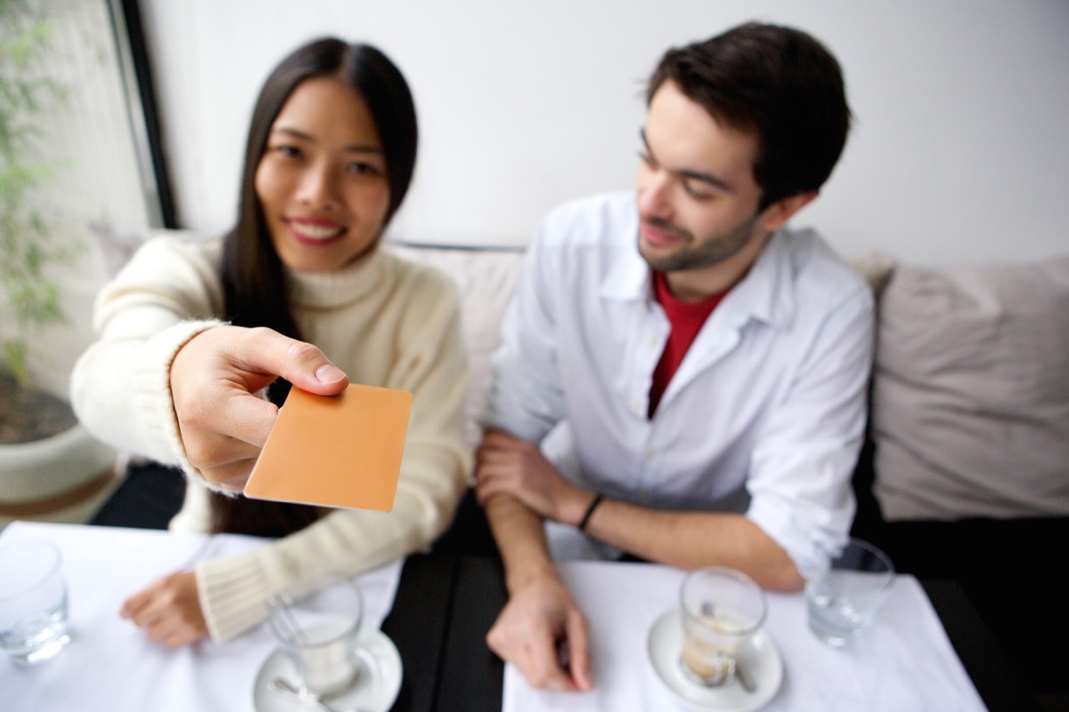 Woman paying with credit card while man checks out her credit card