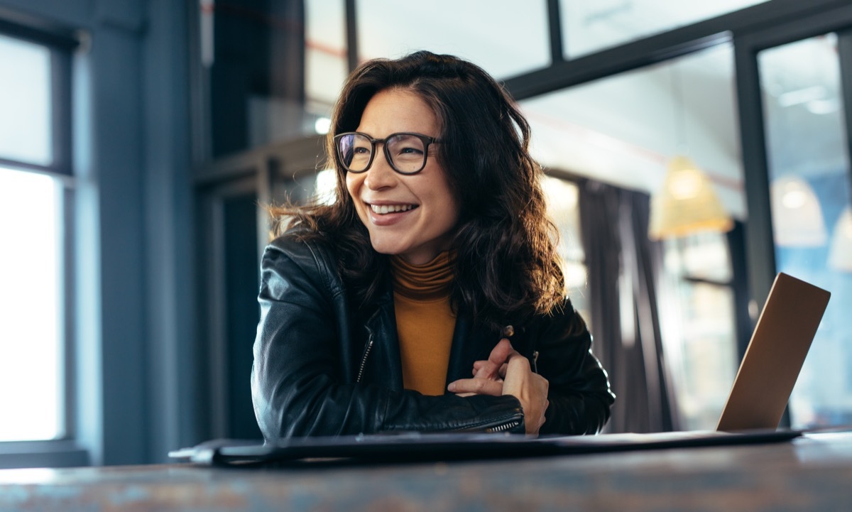 Woman with glasses sitting in office happy and smiling. 