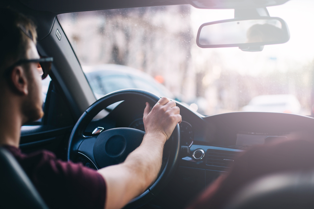 An interior shot of a young man driving a car