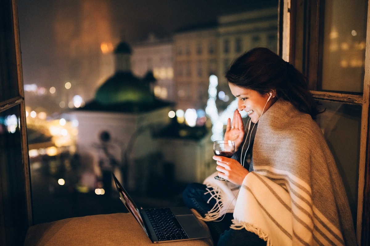 woman enjoying glass of wine over video chat